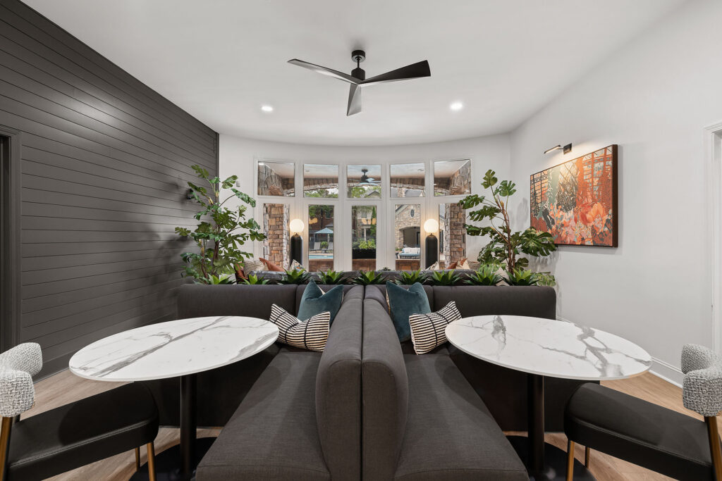 Two back-to-back charcoal grey booths with marble-topped tables in a modern seating area.