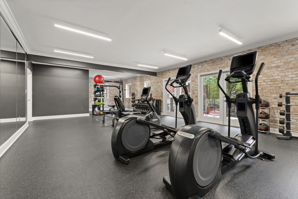 Home gym featuring two elliptical machines, a weight rack, a weight bench, and exercise balls.